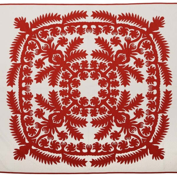 This quilt is asymmetrical with one large red design covering the white background. The design includes diagonal and curvilinear floral designs and shapes. Specifically, pineapples and pineapple leaves.