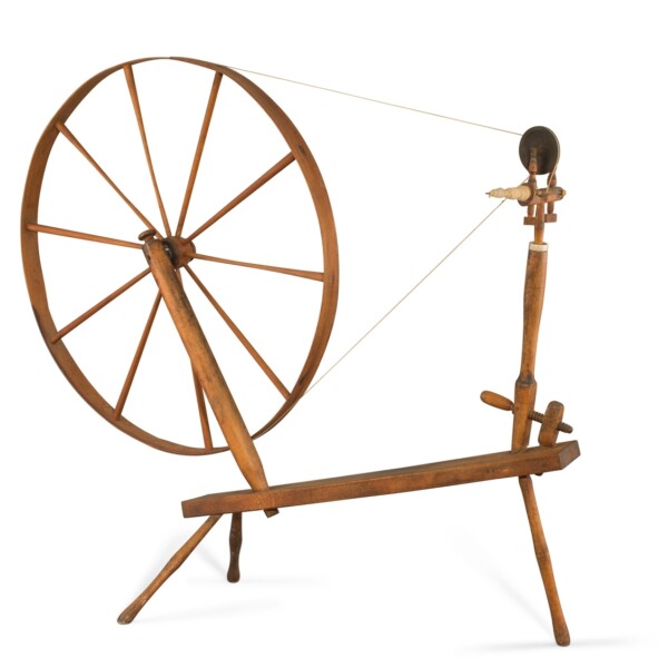 This spinning wheel was made by Shakers, a communal and celibate Protestant community known for their spare, functional, and elegant forms. This spinning wheel is no exception. The large spinning wheel rests on a thin undecorated bench with three legs.