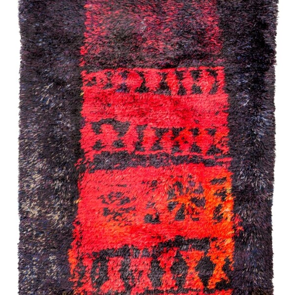 This is a thickly piled rug that consists of red, yellow and orange geometric designs down the center. The outer left and right sides are indigo.