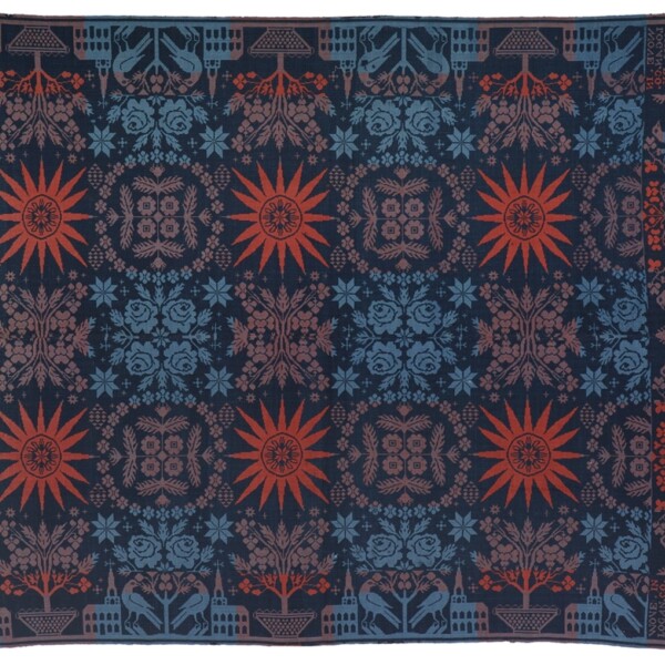 This coverlet is symmetrical with a dark blue background and red, light red and light blue motifs. The pattern includes a church, starbursts, florals, and curvilinear designs.