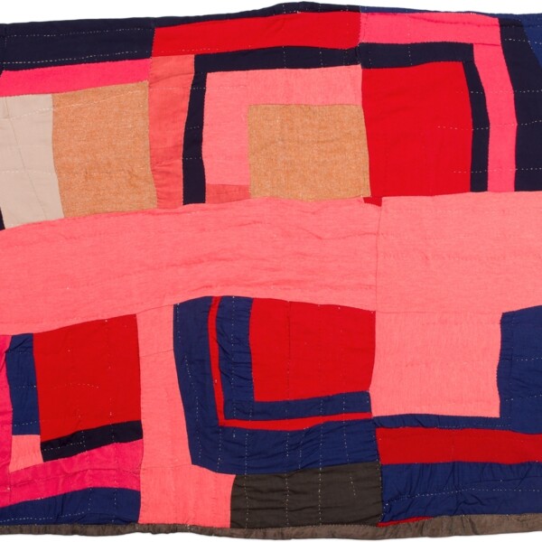 This quilt is asymmetrical with multiple squares and rectangles that vary in size. The rectangles and squares are red, pink, white, light brown, blue and black. There is also a thick pink rectangle running horizontally across the middle of the quilt.